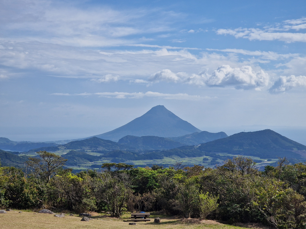 Green forests, with a pyramid formed volcano in the background