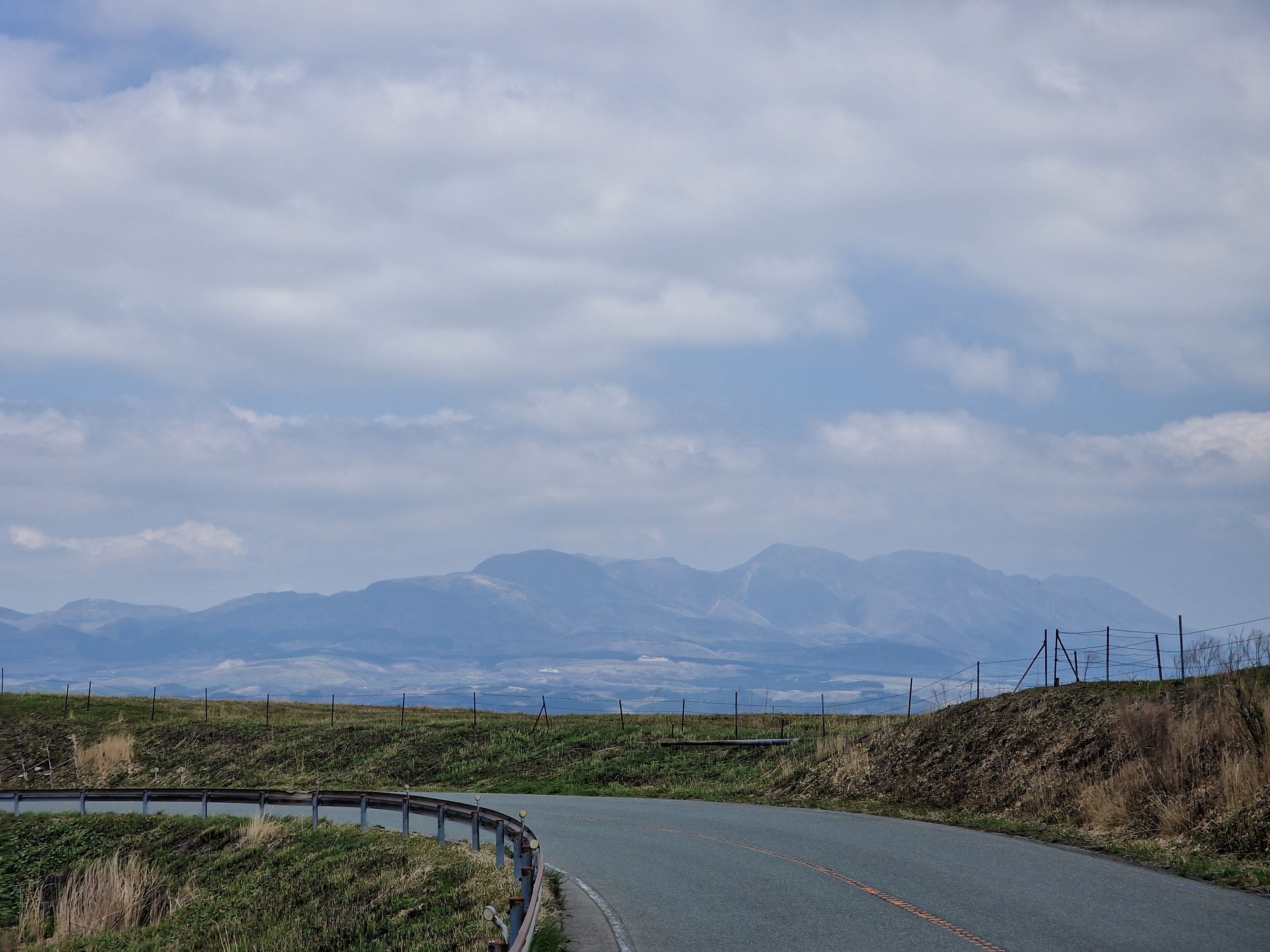 Road going to the left, with a long mountain range in the distance