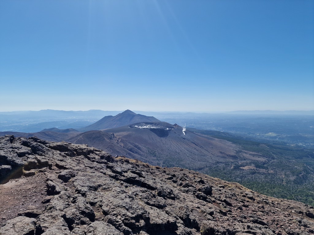 A flat volcano in the distance with smoke coming out of it