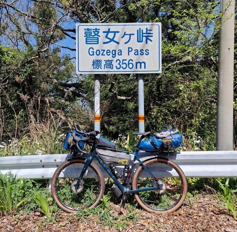 My bike leaning on a sign saying Gozega Pass 356m