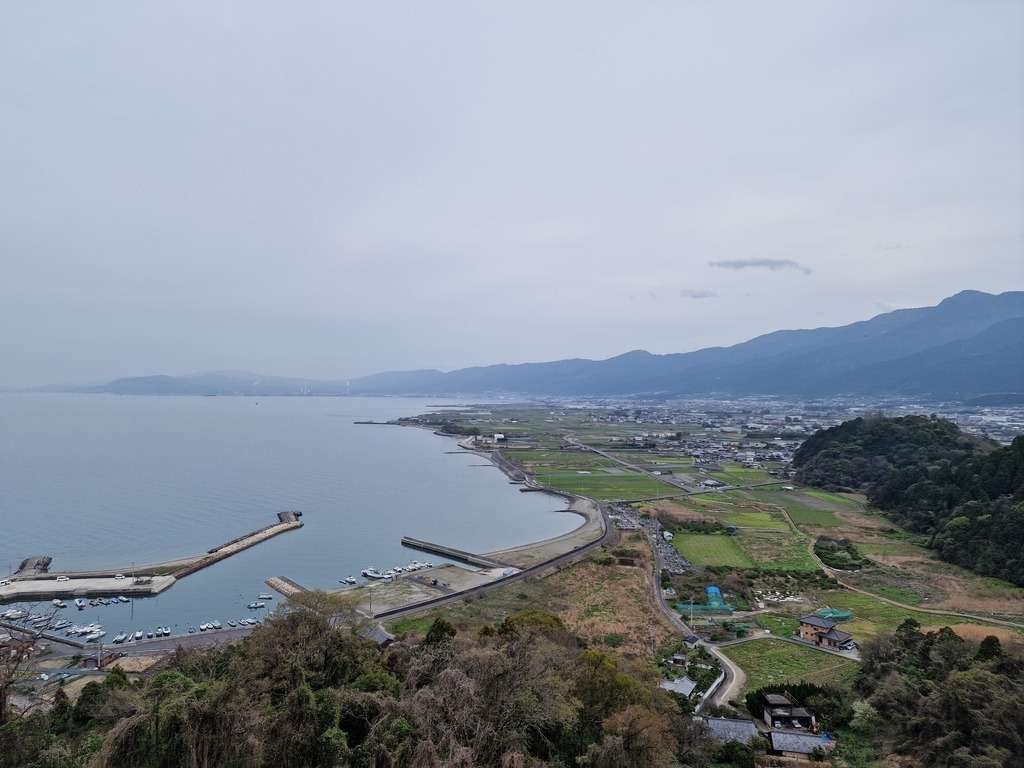 View of a bay with a mix of farmland, city, and mountains in the far