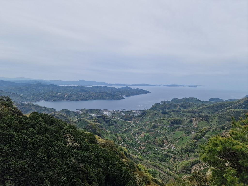 View from the top of a mountain, overlooking farmed hills and the sea