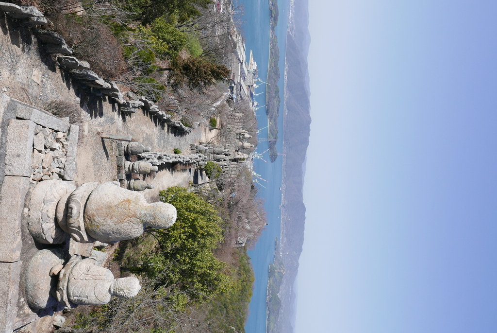 View of several arhats next to a walking path on top of a small mountain.