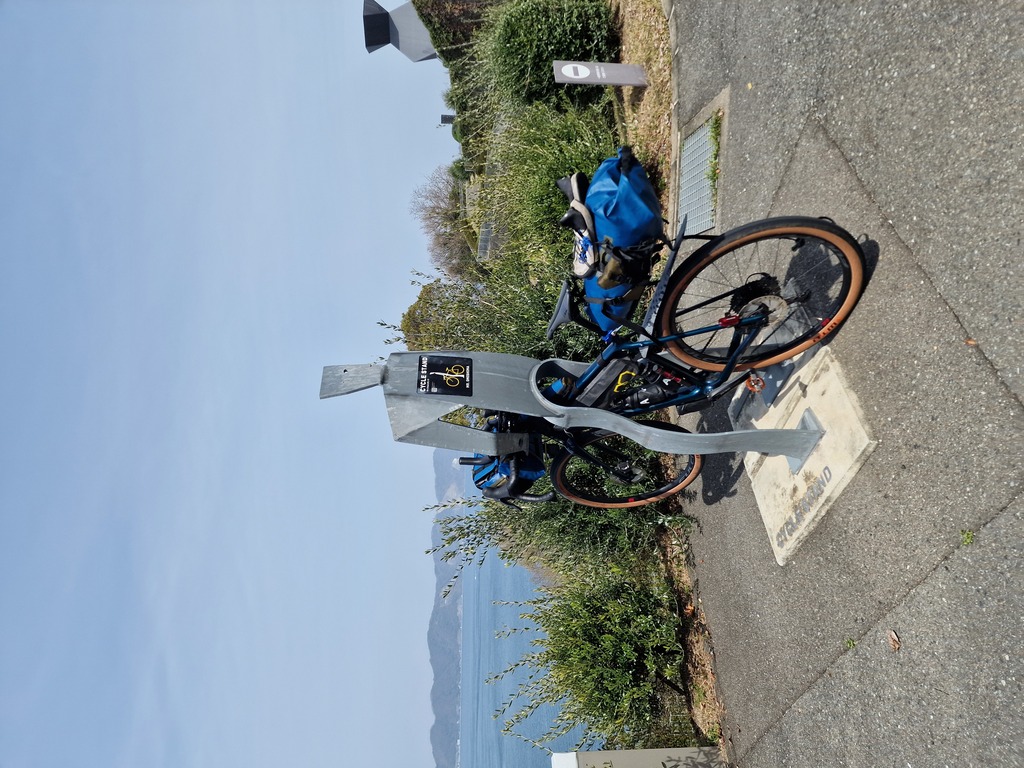 A metal bike stand shaped as a human looking out at the sea.