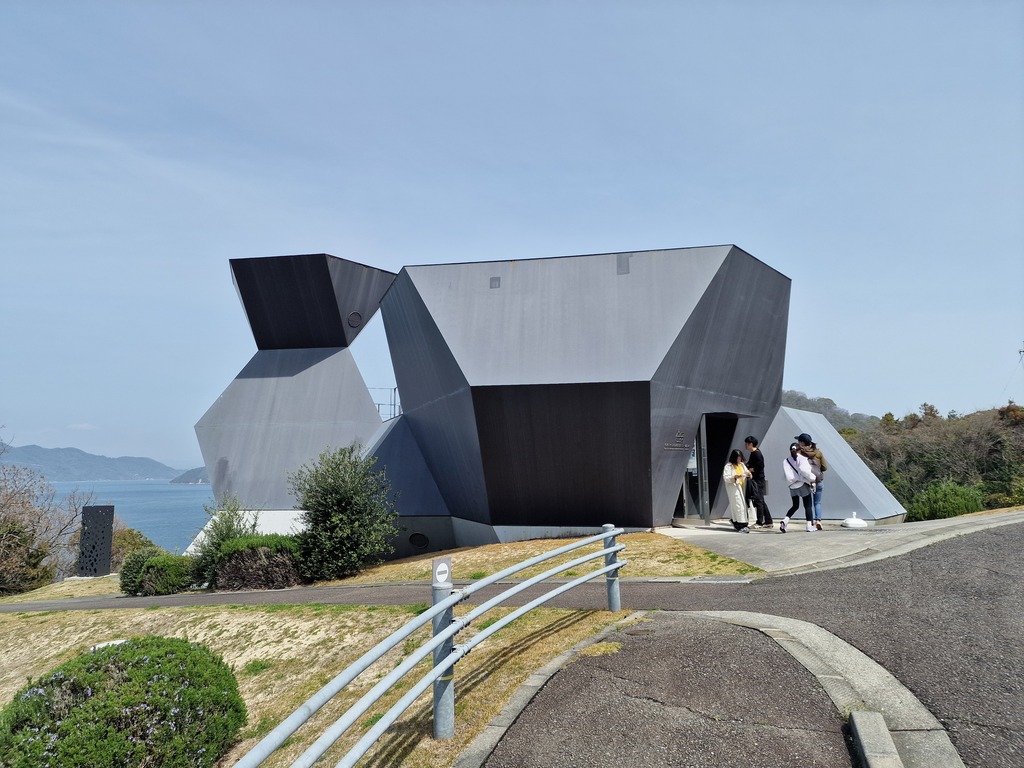 A strange formed building, looking like it is made out of metal.