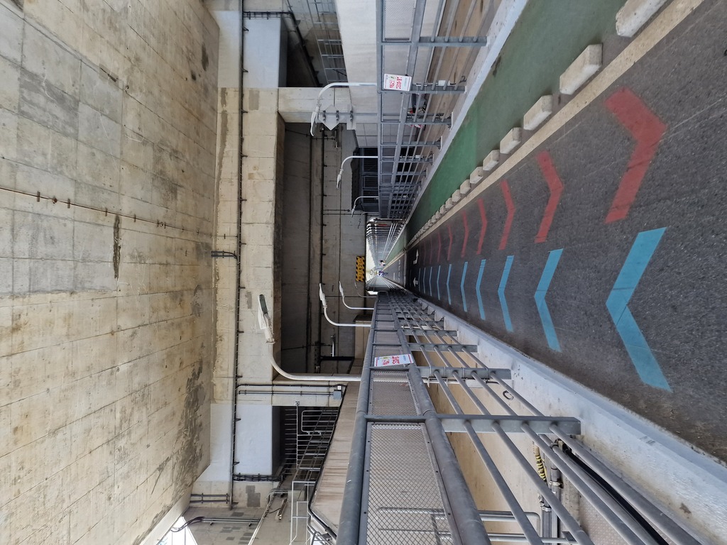 View of the bike path underneath a car bridge, the road is split in three, two for each cycling direction, and one for walking.